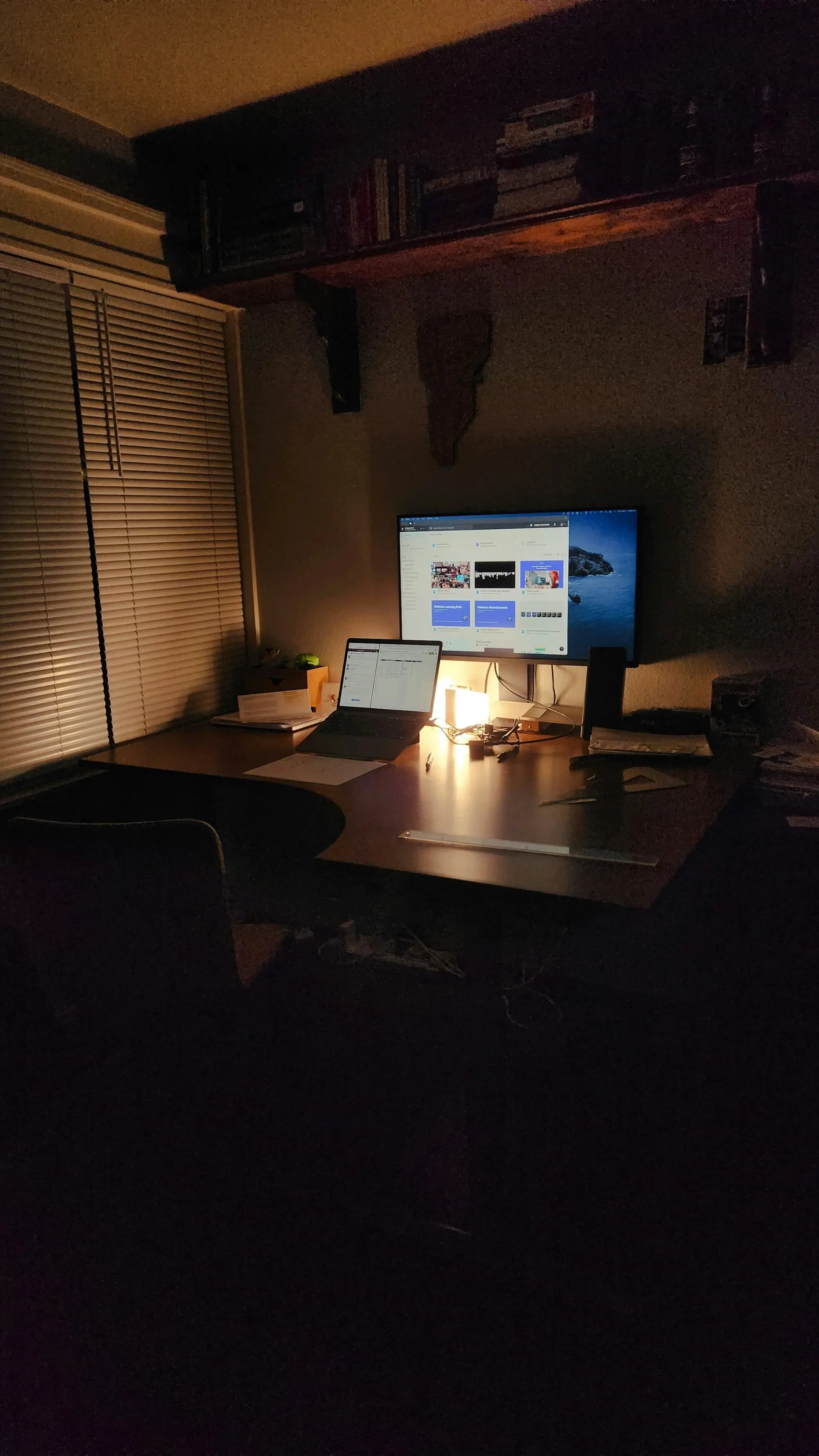 A dimly lit desk with a laptop and monitor